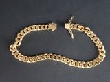 a close up of a gold chain bracelet on a black surface