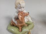 a small figurine of a boy sitting on a pillow with a dog