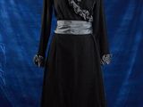 une robe noire posée sur un mannequin, devant un fond bleu