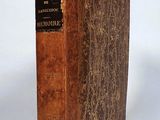 an old book sitting on top of a white table next to a white wall