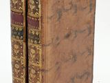 two old books sitting on top of each other on a white surface