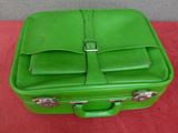 a green suitcase sitting on a table with a red table cloth