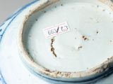 a blue and white vase with a tag on it