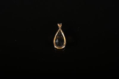 un pendentif doré en forme de larme sur fond noir