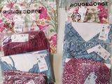 Trois sacs de vêtements sont posés sur une table, avec leurs étiquettes encore attachées.