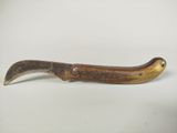 une image représentant un couteau en bois muni d'un long manche, posé sur une surface blanche