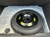 a tire in the trunk of a car with a yellow sticker on it
