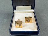pair of gold tone cufflinks in a blue box on a table