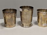 quatre tasses en argent sont alignées sur une surface blanche
