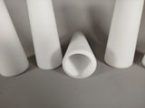 several white pipes are lined up in a row on a gray surface