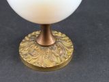 a white glass cup sitting on top of a gold plate