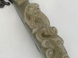 a green jade carving of a woman on a long knife