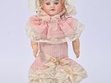 a small doll that is wearing a pink dress and hat