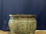 an old bronze pot sitting on top of a wooden floor next to a blue curtain