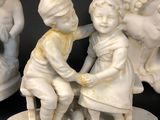 three figurines of children sitting on a bench