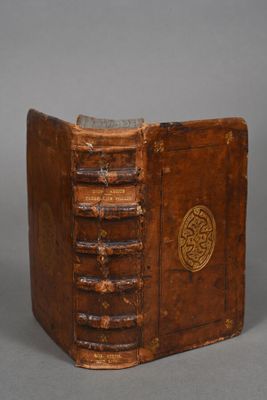 an old brown book sitting on top of a table next to a cup