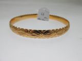 gros plan d'un bracelet en or sur une surface blanche