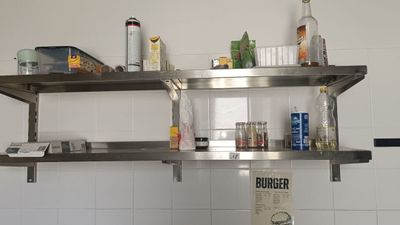 une étagère métallique sur laquelle sont posées des bouteilles, dans une cuisine