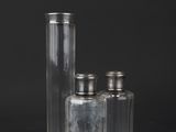 three clear glass bottles with silver lids on a black background