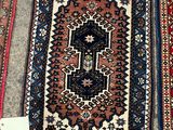 trois tapis orientaux exposés sur un trottoir, accompagnés d'étiquettes