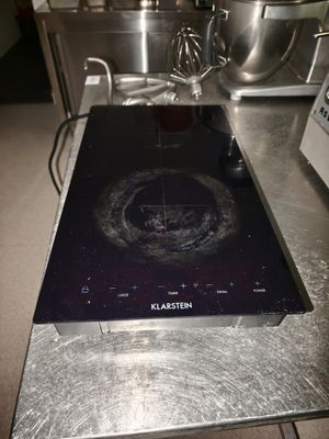 une plaque de cuisson noire posée sur un plan de travail en métal dans une cuisine