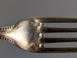 a silver fork with a metal handle on a gray surface