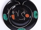 une image représentant une assiette noire ornée de motifs verts et orange
