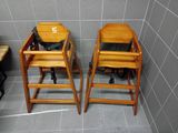 two wooden high chairs in a bathroom with a black bag on them