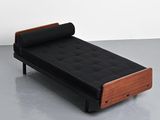 black leather daybed with wooden frame and foot rest on grey floor