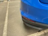 the rear end of a blue car parked in a parking lot