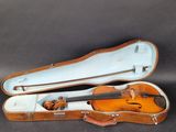 un vieil étui à violon contenant un violon, posé sur une table