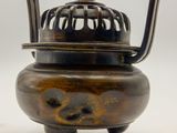 an image of a small bronze pot with a handle on a white background