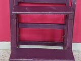 a purple wooden step stool in front of a pink wall