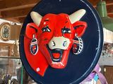 a red bull head on a blue plate hanging from a wooden pole