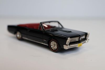 une petite voiture noire avec un toit rouge posée sur une surface blanche