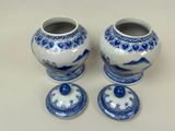 two blue and white vases with lids on a table