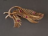 un gros plan sur une broche en feuille d'or sertie de pierres roses