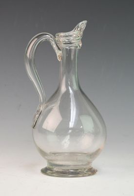 a clear glass pitcher with a handle on a table