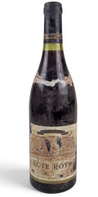 an old bottle of wine sitting on top of a white surface