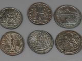 six different coins are shown in a row on a white surface