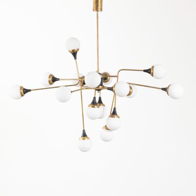 un lustre en laiton orné de globes en verre blanc suspendu au plafond