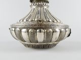 a silver vase with a bird on top of it