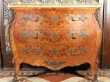 une commode en bois dans une pièce avec du papier peint à motifs floraux