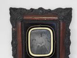 an old photo of a woman in a black dress in a wooden frame