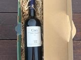 une bouteille de vin dans un carton, posée sur une table en bois