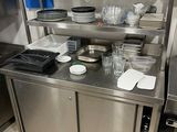 une cuisine en inox avec de nombreux plats et ustensiles posés sur le plan de travail