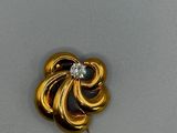 une photo d'une broche en or ornée d'un diamant au centre