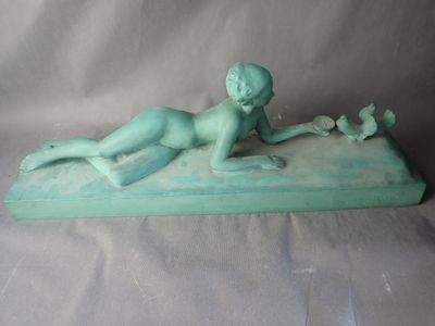 une petite statue représentant un garçon allongé sur une planche de surf