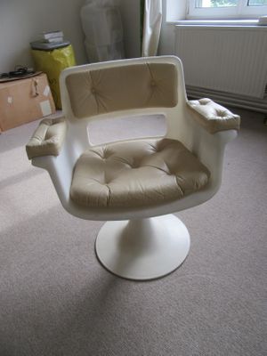 a white chair in a room with a window in the background