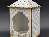 une image représentant une boîte blanche et dorée surmontée d'un oiseau
